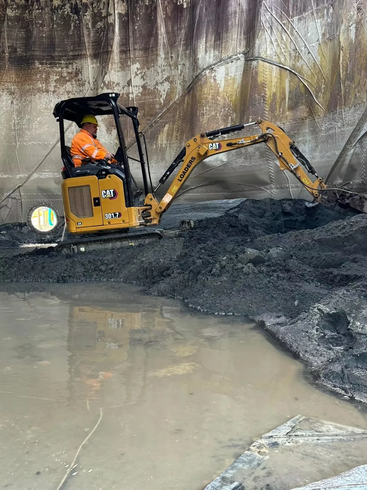 Mini excavator working inside a tank during strip out