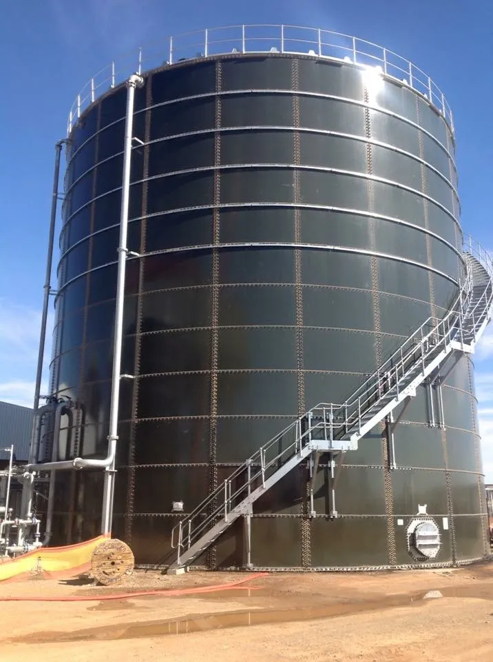 A completed dark green bolted steel tank with an access staircase running up its side