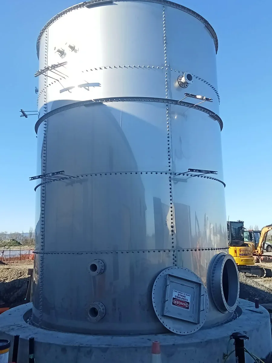 Tall galvanised bolted steel tank standing on a build site