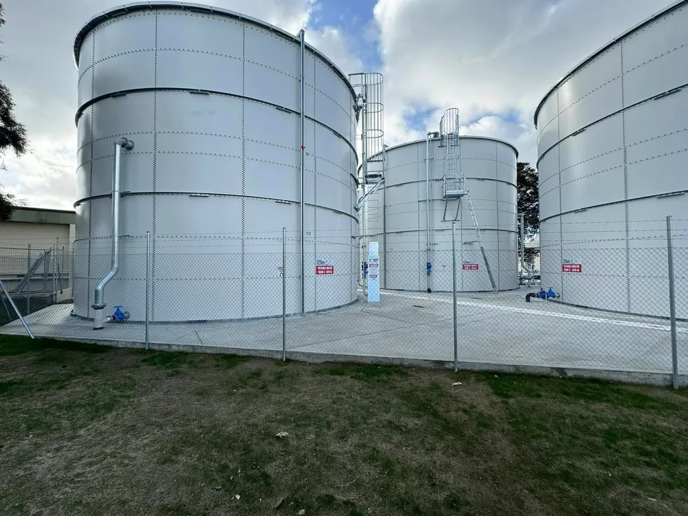 Row of white bolted steel tanks on a completed municipal site