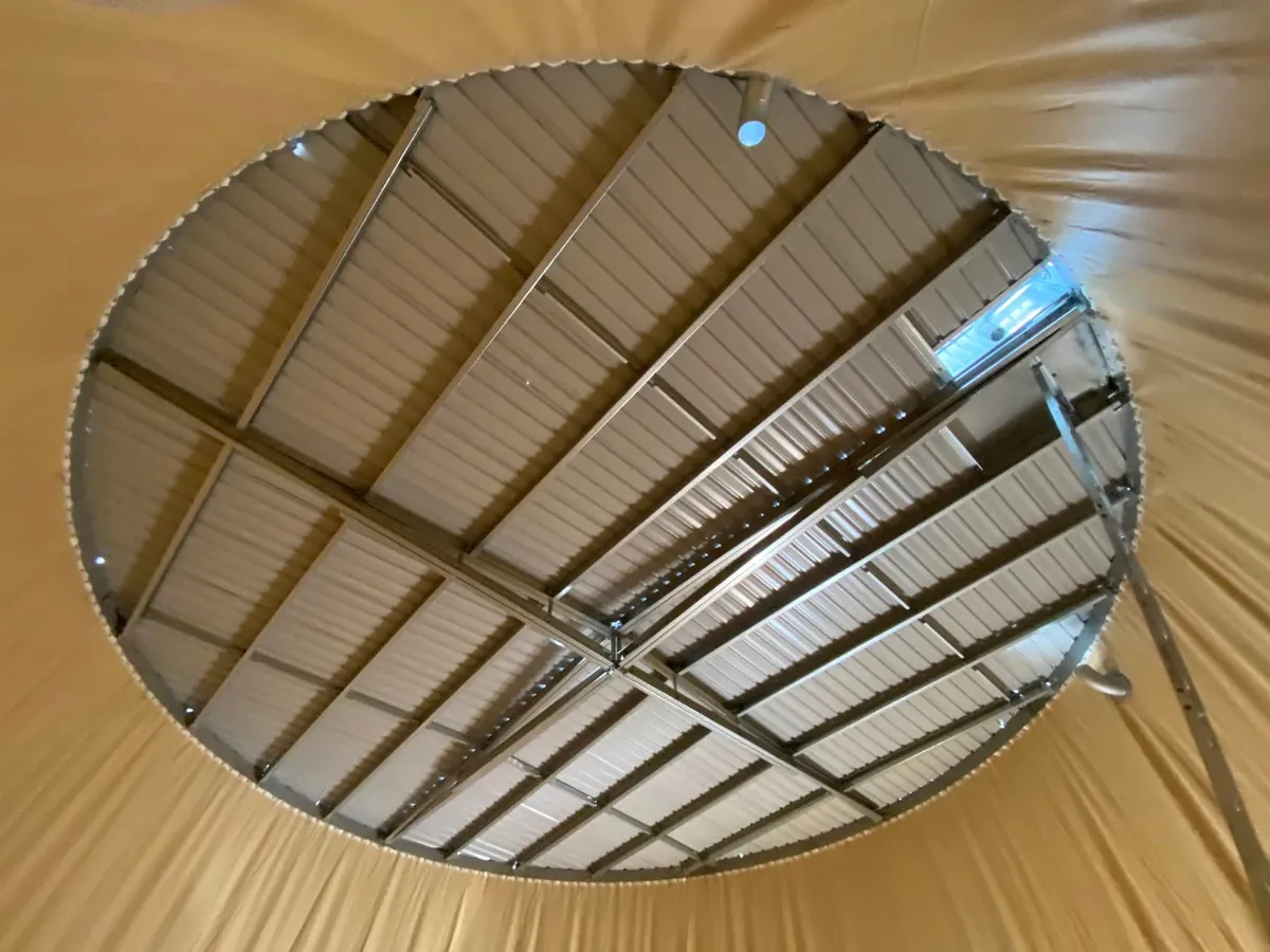 Looking up from inside a lined tank at the roof structure and the open hatch above