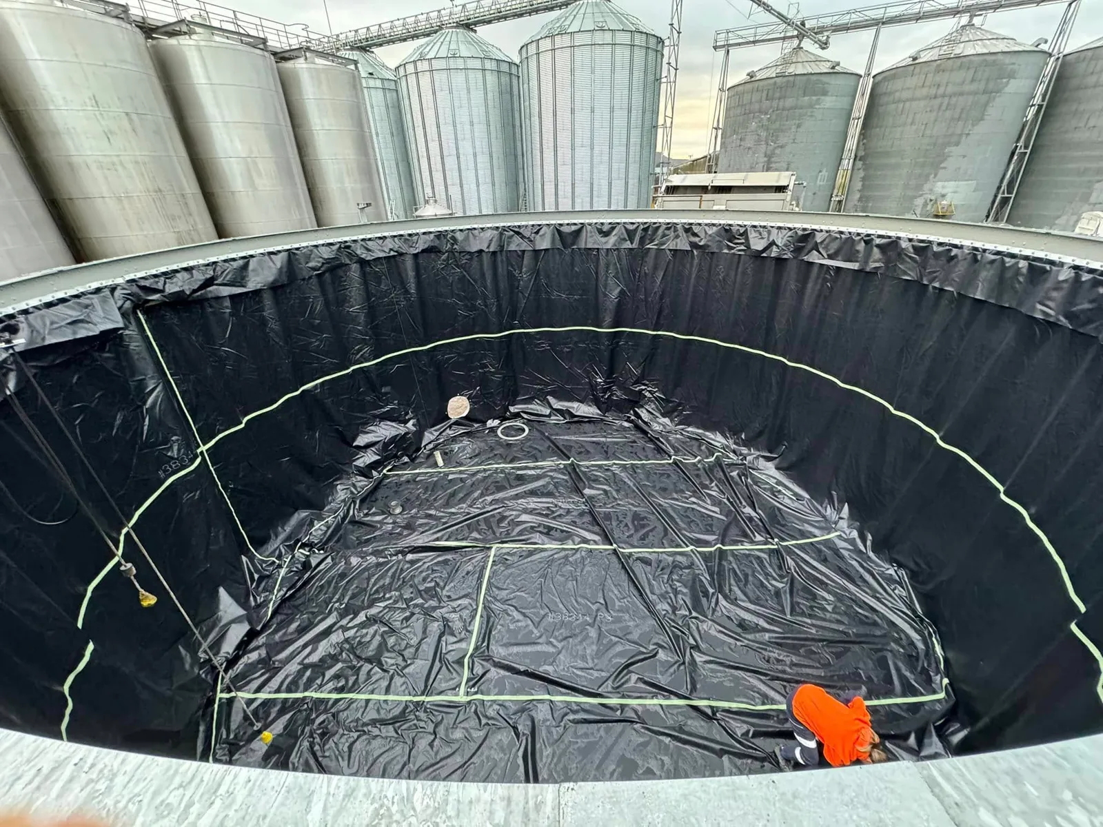 The new black liner laid out across the tank floor, a crew member working the edge into the wall
