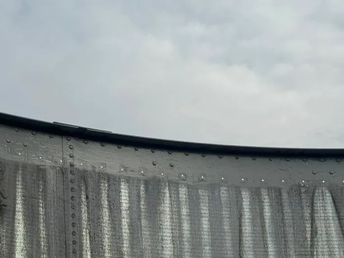The same wall with the top course recoated, the new grey band running around the rim above the old panels