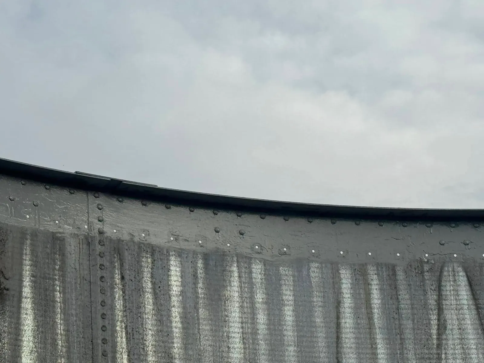 The same wall with the top course recoated, the new grey band running around the rim above the old panels