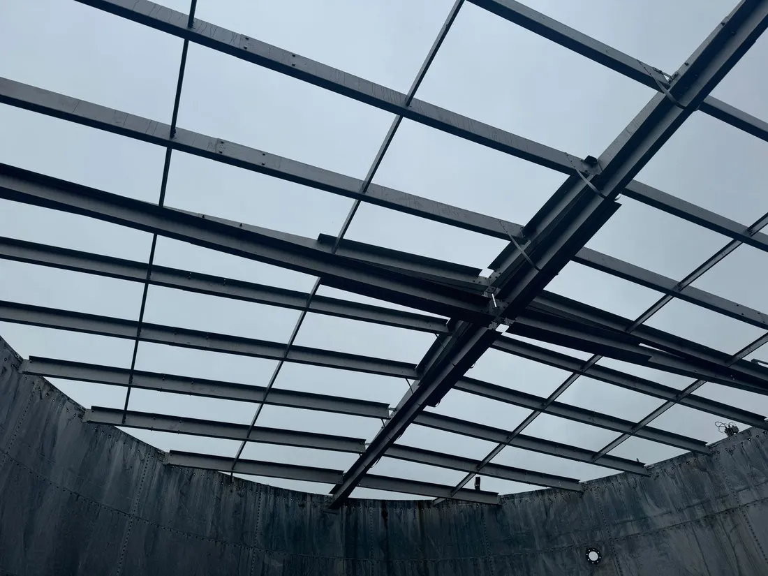 Steel roof rafters spanning the inside of a tank shell against the sky